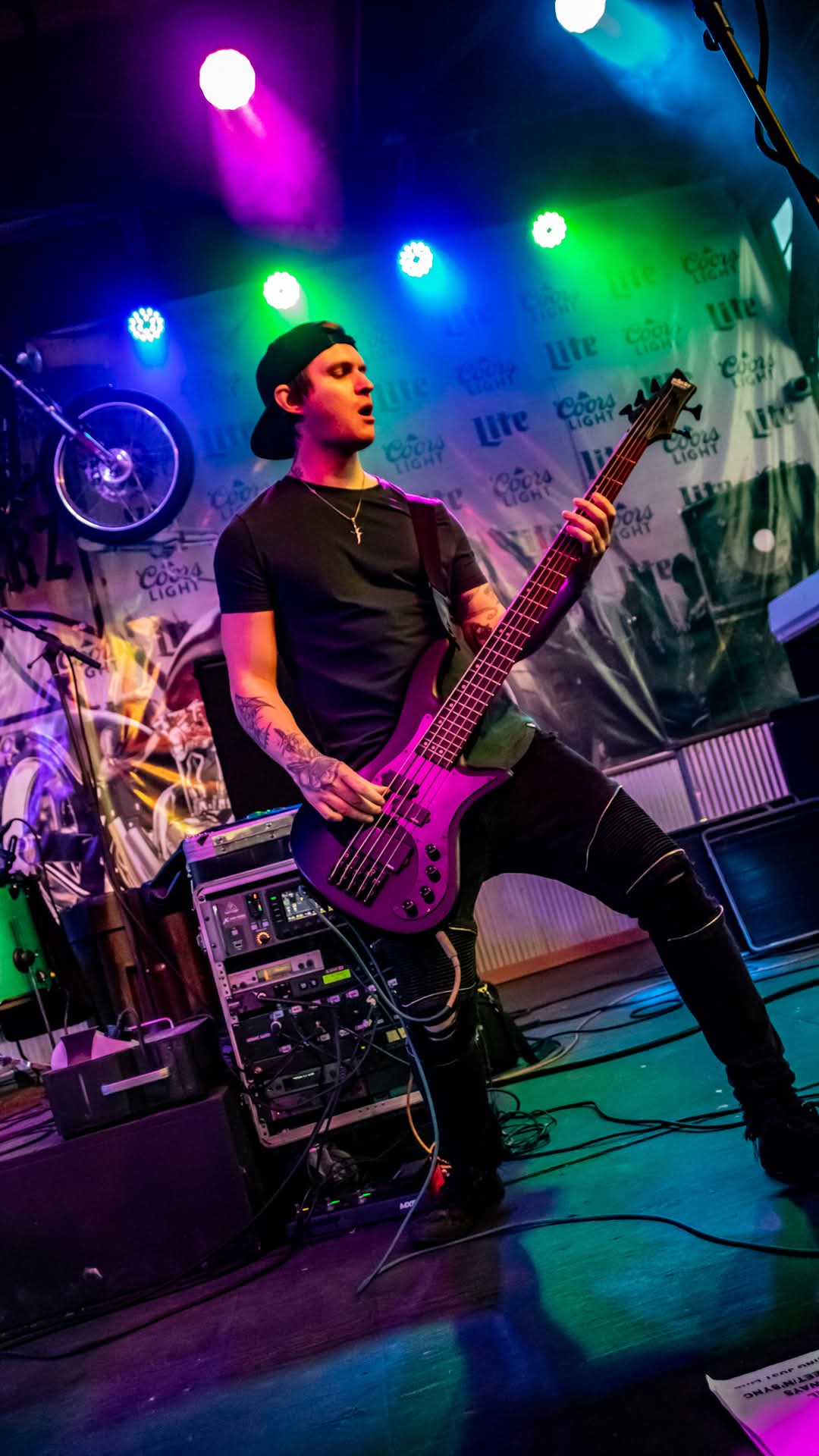 Bassist striking a wide stance under multicolor stage lights