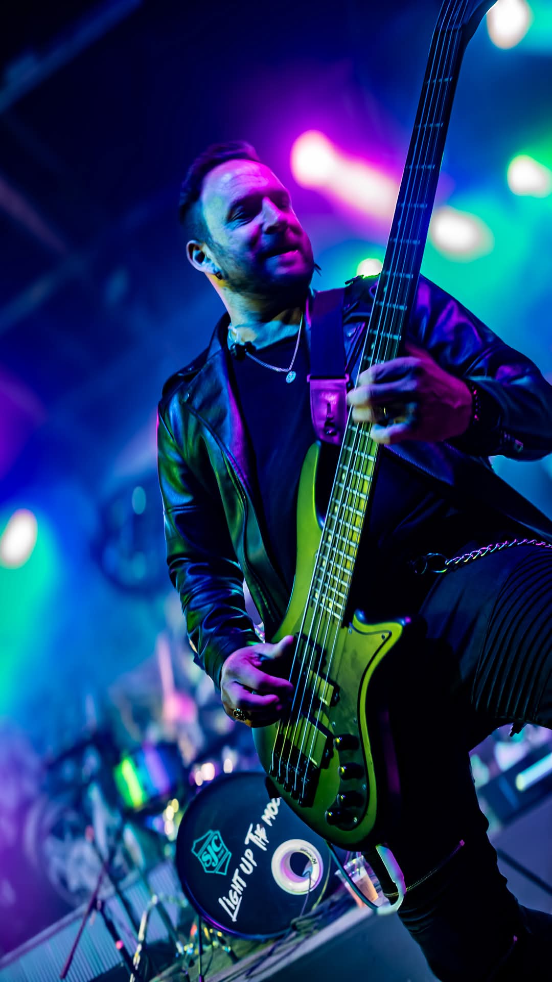 Bassist with green bass behind the Light Up The Moon kick drum