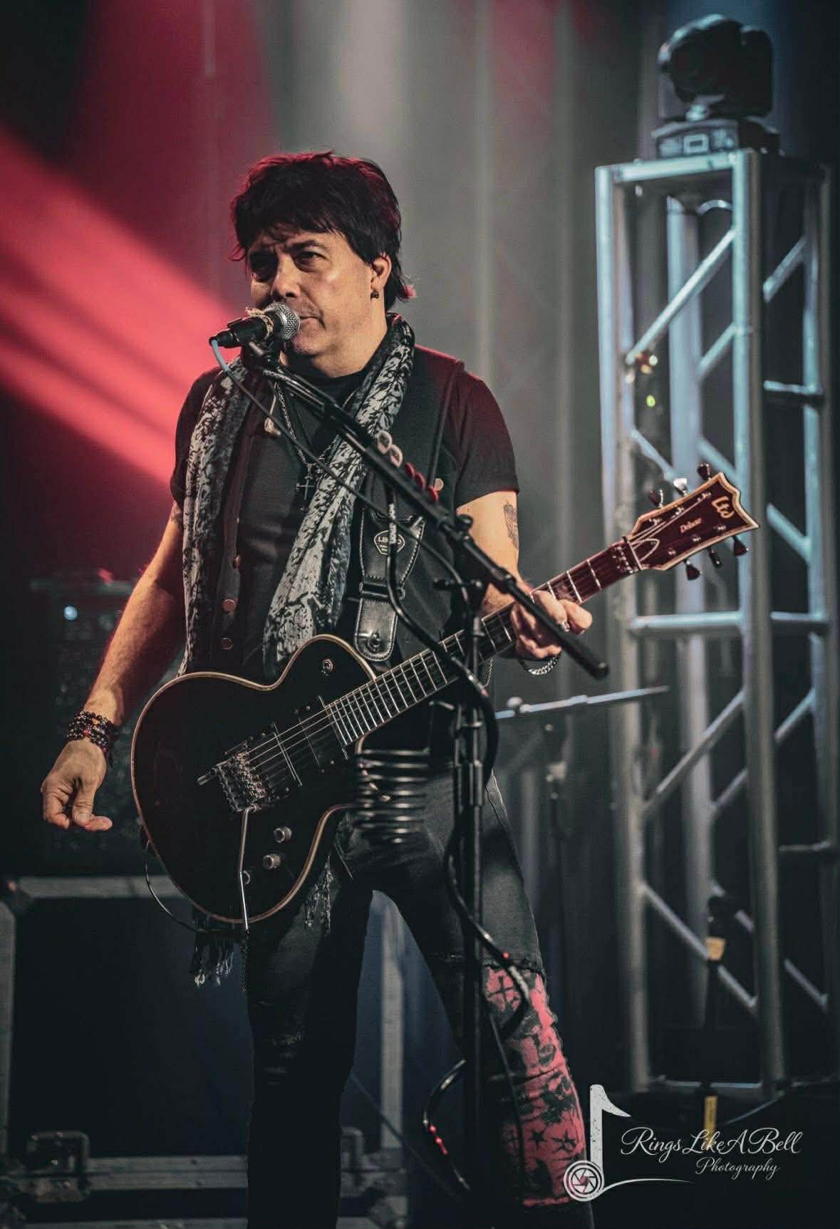 Lead vocalist and guitarist singing into the mic on a large stage