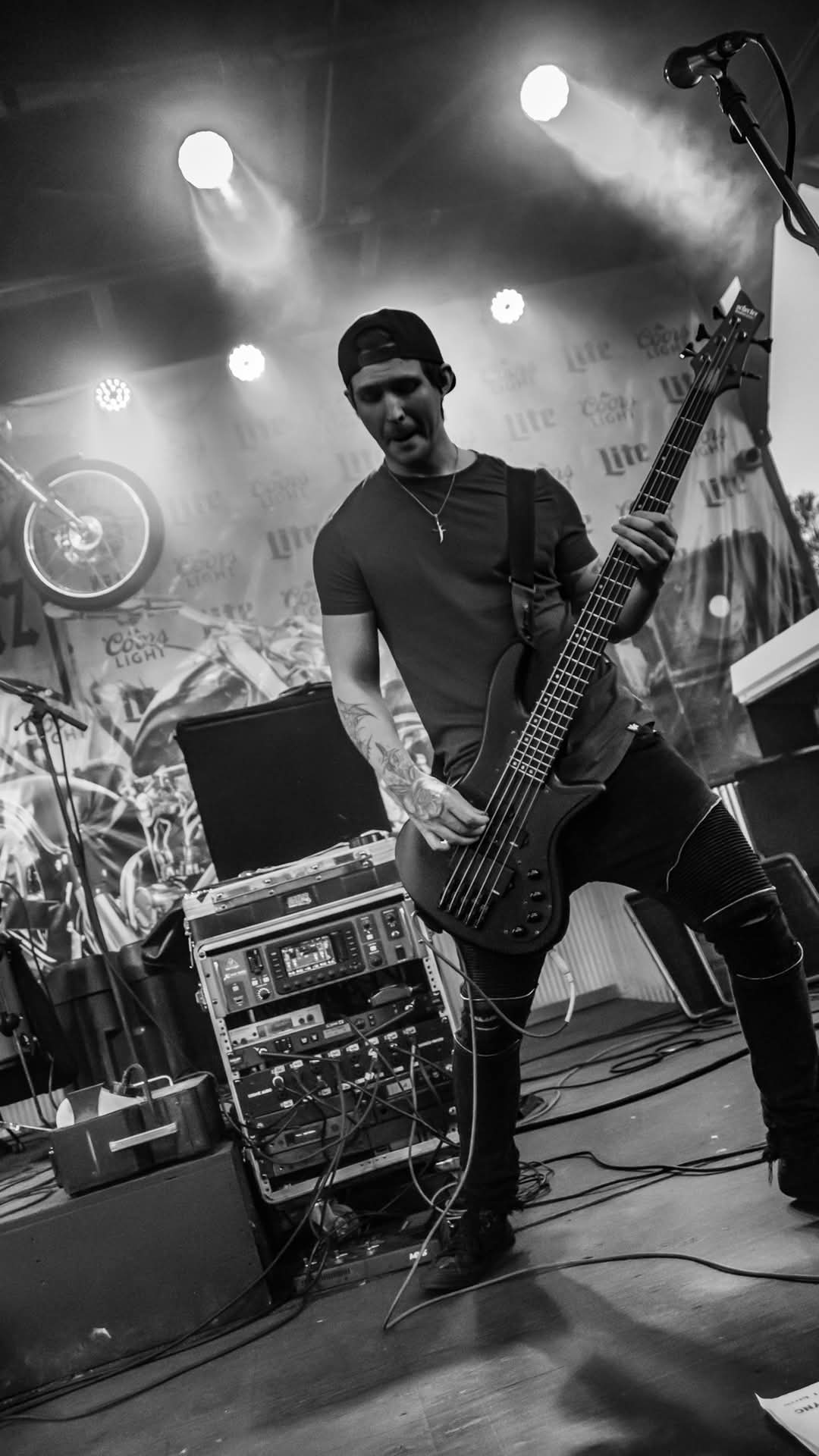 Bassist mid-performance under bright stage lights — black and white