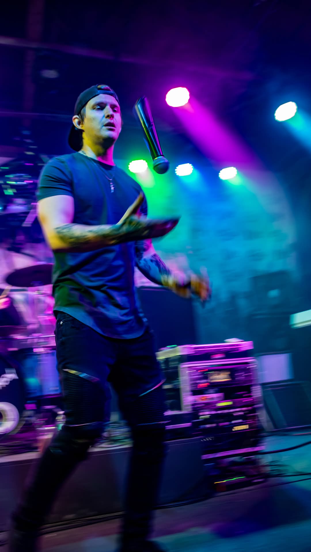 Vocalist tossing the mic mid-air under blue and purple stage lights