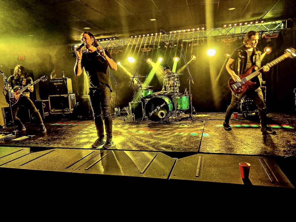 Full band on stage under yellow lights — wide shot