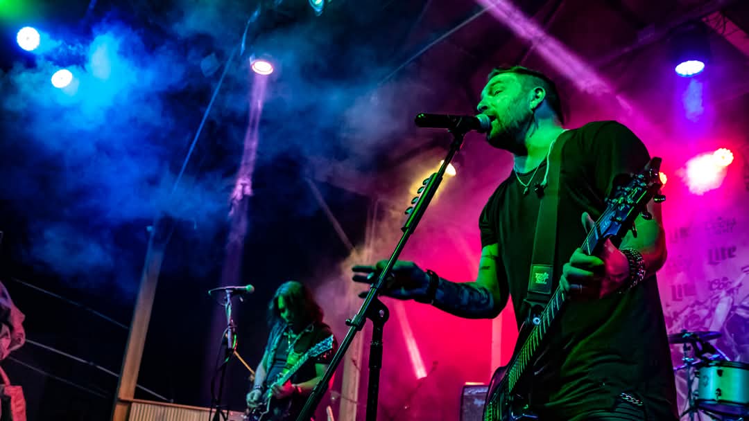 Vocalist at the mic with guitar under blue and red stage lights