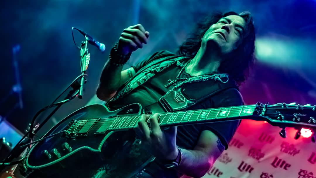 Lead guitarist mid-solo head back under green stage light