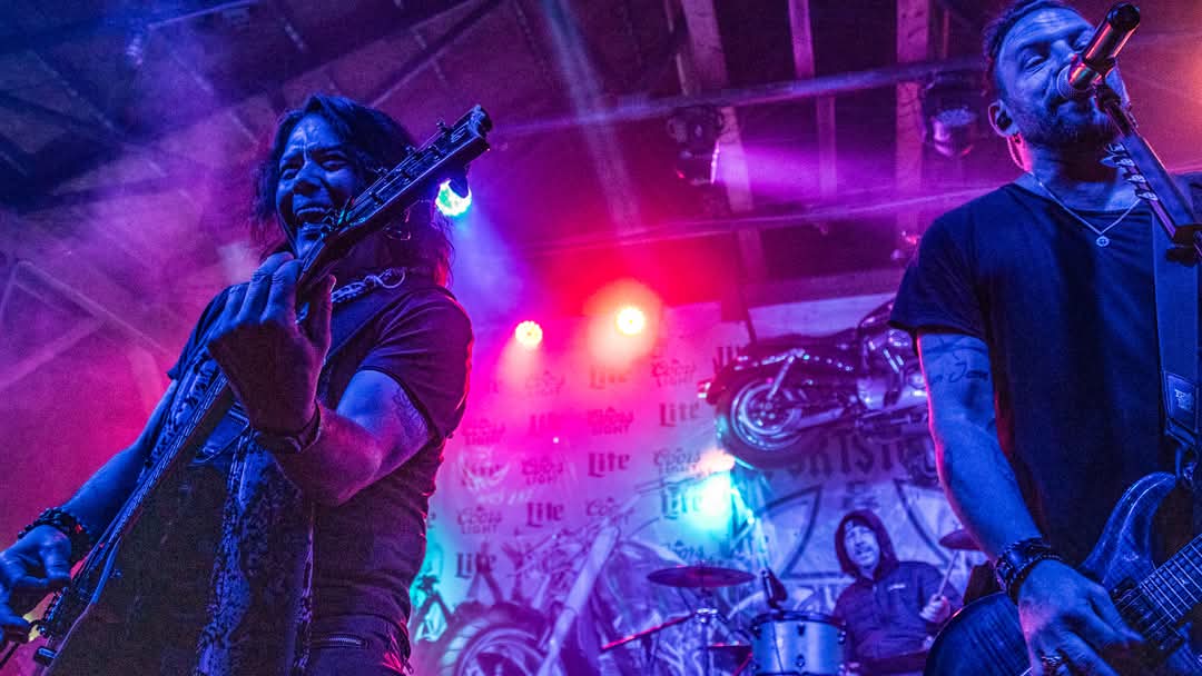 Guitarist and vocalist performing together under purple and red lights